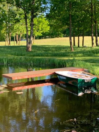 un pequeño barco sentado en el agua con un banco en Komfortowy domek z kominkiem en Barwice