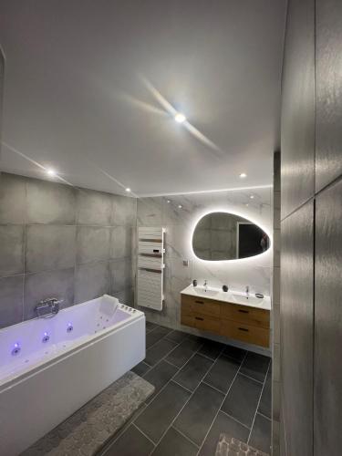 une salle de bain avec une baignoire, un lavabo et un miroir dans l'établissement la vallées du tuffeau, à Bourré