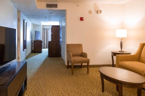 a living room with a couch and chairs and a tv at Hilton Garden Inn Orlando East - UCF Area in Orlando