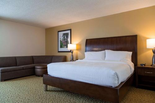 a hotel room with a bed and a couch at Hilton Garden Inn Orlando East - UCF Area in Orlando