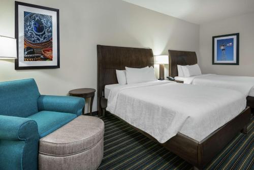 una habitación de hotel con 2 camas y una silla en Hilton Garden Inn San Antonio/Rim Pass Drive en San Antonio