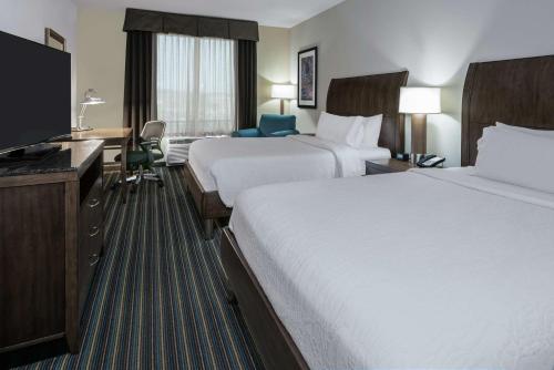 a hotel room with two beds and a flat screen tv at Hilton Garden Inn San Antonio/Rim Pass Drive in San Antonio