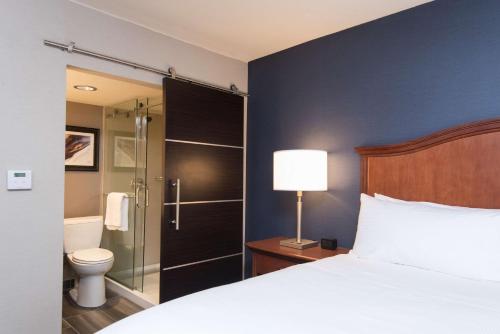 a bedroom with a bed and a shower and a toilet at DoubleTree by Hilton Schenectady in Schenectady