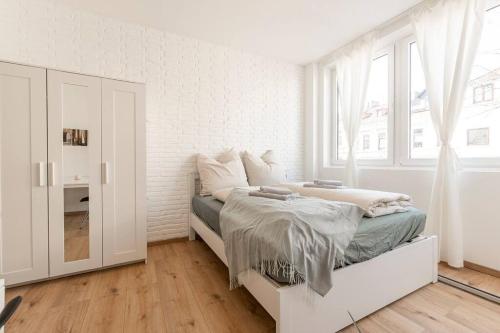 a white bedroom with a bed and a window at Stilvolle Wohnung zentral Bremen in Bremen