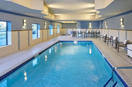 uma piscina num hotel com cadeiras e mesas em Hampton Inn & Suites Milwaukee/Franklin em Franklin