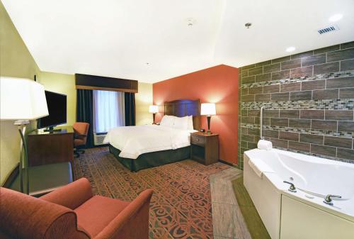 a hotel room with a bed and a bath tub at Hampton Inn & Suites Milwaukee/Franklin in Franklin