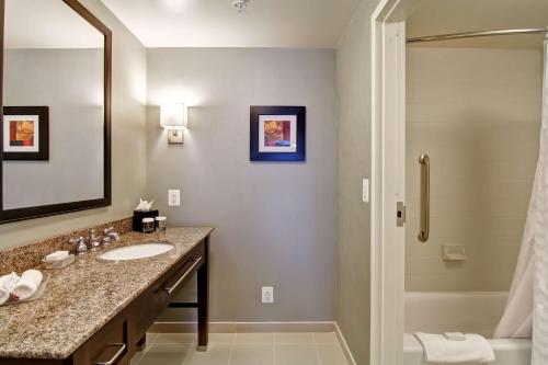 a bathroom with a sink and a mirror and a tub at Homewood Suites by Hilton Woodbridge in Woodbridge