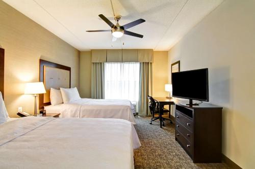 a hotel room with two beds and a flat screen tv at Homewood Suites by Hilton Woodbridge in Woodbridge