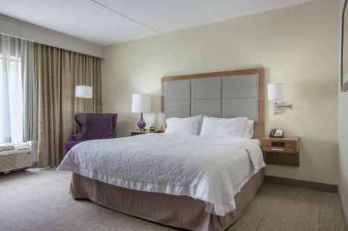 a hotel room with a large bed and a purple chair at Hampton Inn & Suites - Knoxville Papermill Drive, TN in Knoxville