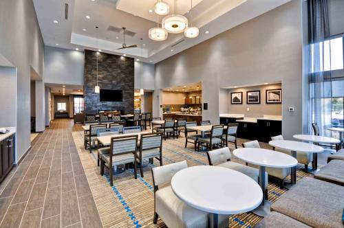 a waiting room with tables and chairs and a fireplace at Homewood Suites by Hilton Cincinnati/West Chester in West Chester