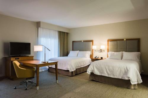 a hotel room with two beds and a desk and a television at Hampton Inn & Suites - Knoxville Papermill Drive, TN in Knoxville