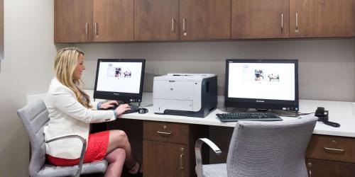 a woman sitting at a desk with two computer monitors at Hampton Inn & Suites - Knoxville Papermill Drive, TN in Knoxville