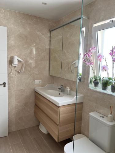 a bathroom with a sink and a toilet and a mirror at Casa Costa Bella in Costa Teguise