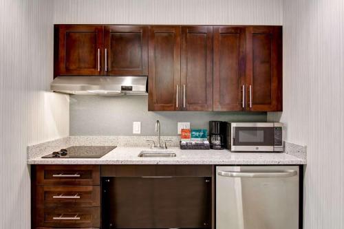 a kitchen with wooden cabinets and a sink and a microwave at Homewood Suites By Hilton Clifton Park in Clifton Park