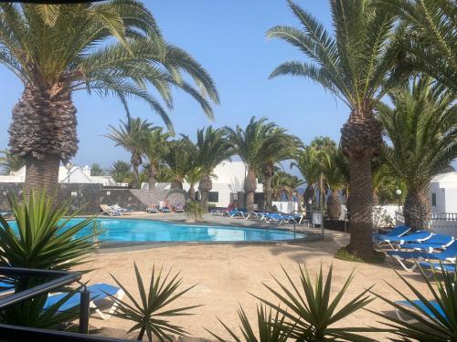 un complejo con piscina con palmeras y tumbonas en One bedroom bungalow Playa Bastian Costa Teguise, en Costa Teguise