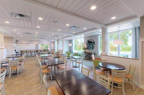 uma sala de jantar com mesas, cadeiras e janelas em Hampton Inn Bar Harbor em Bar Harbor