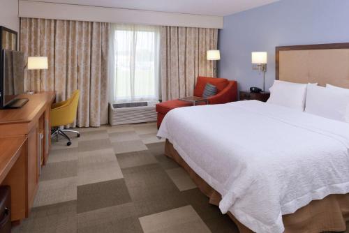 a hotel room with a large bed and a television at Hampton Inn & Suites by Hilton Lonoke in Lonoke