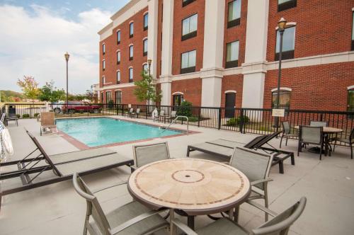 une terrasse avec une table, des chaises et une piscine dans l'établissement Hampton Inn Hernando, MS, à Hernando