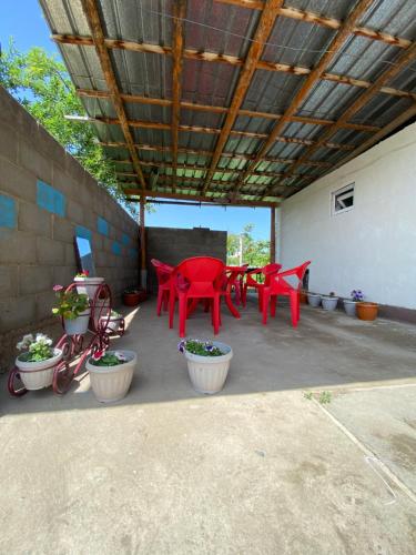 a patio with red tables and chairs and potted plants at Tunuk Guest House in Tossor