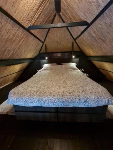 een groot bed in een kamer met een houten plafond bij B&B Bos en Wei XL in Hall