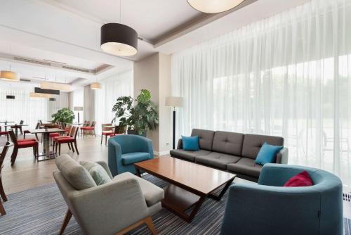 a living room with a couch and chairs and a table at Hampton by Hilton Krakow in Krakow