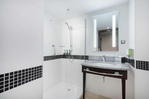 a bathroom with a sink and a shower and a mirror at Hampton by Hilton Krakow in Krakow