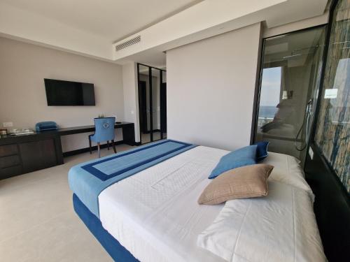 a bedroom with a large bed and a tv at Ngonia Bay Boutique Hotel in Milazzo