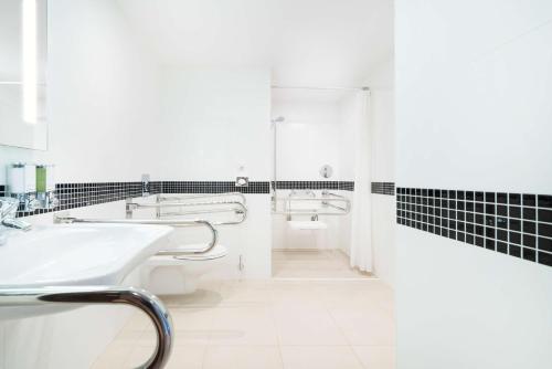 a white bathroom with a sink and a shower at Hampton by Hilton Krakow in Kraków