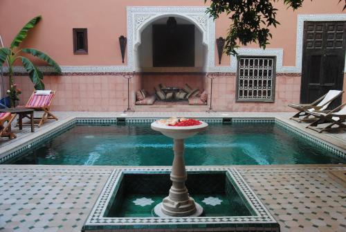 a pool with a bowl of fruit on a pedestal in a house at Riad Barroko in Marrakech