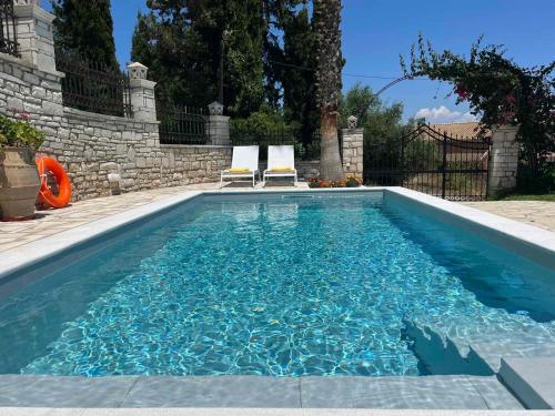 a swimming pool with two chairs in a backyard at Casa StaLa in Kastanéa
