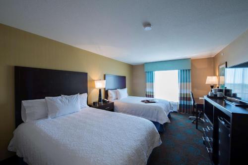 a hotel room with two beds and a window at Hampton Inn Saskatoon South in Saskatoon