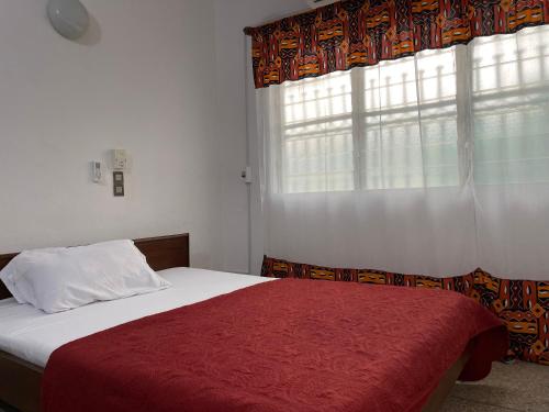 a bedroom with a bed with a red blanket and a window at La Villa René in Porto-Novo