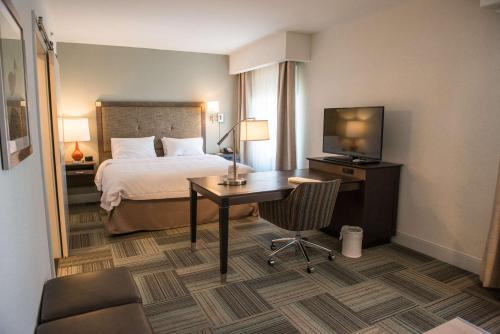a hotel room with a bed and a desk with a television at Hampton Inn Bainbridge, GA in Bainbridge