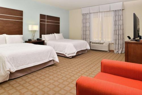 a hotel room with two beds and a couch at Hampton Inn and Suites Hutto in Hutto