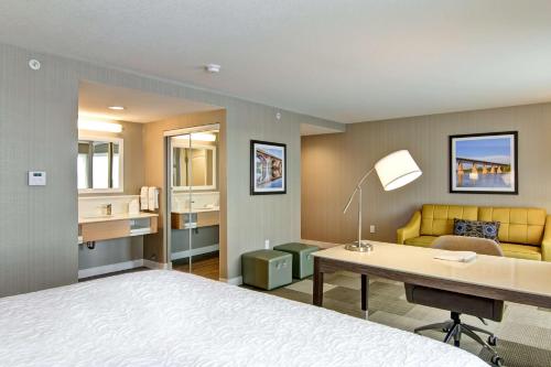 a hotel room with a bed and a desk and a couch at Hampton Inn & Suites by Hilton Saskatoon Airport in Saskatoon
