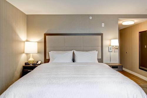 a bedroom with a large white bed with two lamps at Hampton Inn & Suites by Hilton Saskatoon Airport in Saskatoon