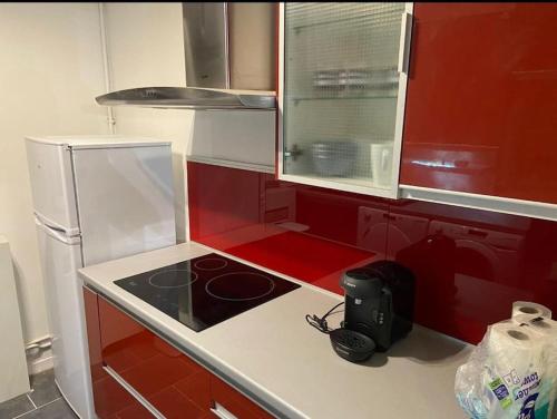 - une cuisine avec des murs rouges et une cuisinière four supérieur dans l'établissement Appartement T4 Rouen, à Rouen
