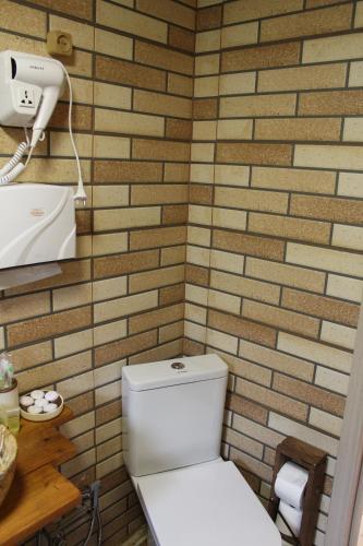 a bathroom with a toilet and a brick wall at mood villa Kazbegi in Stepantsminda