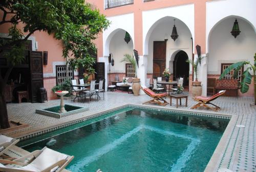 a pool in a courtyard with chairs and tables at Riad Barroko in Marrakesh