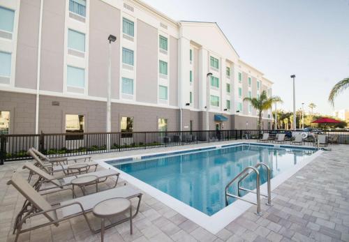 a pool at a hotel with chairs and a building at Hampton Inn & Suites Orlando near SeaWorld in Orlando