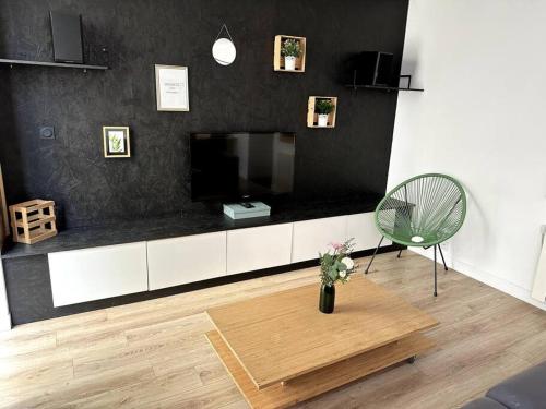 una sala de estar con TV y un jarrón de flores en Le Forum - HYPER centre - PARKING, en Reims