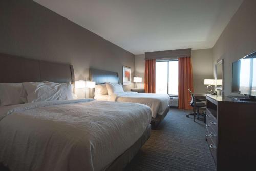a hotel room with two beds and a flat screen tv at Hilton Garden Inn Bolingbrook I-55 in Bolingbrook