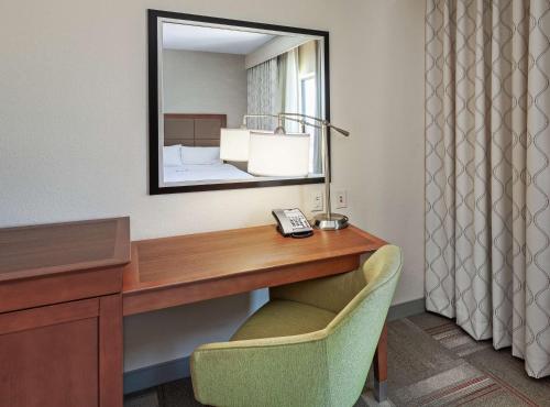 a desk in a hotel room with a mirror and a chair at Hampton Inn & Suites Claremore in Claremore