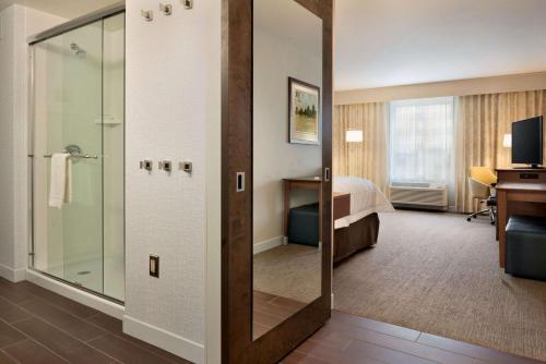 a hotel room with a shower and a bedroom at Hampton Inn Lincoln Airport, Ne in Lincoln