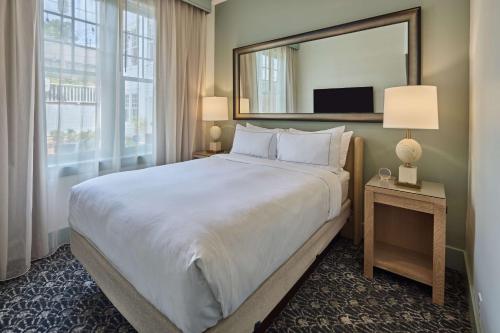a large bed in a hotel room with a large mirror at The Partridge Inn Augusta, Curio Collection by Hilton in Augusta