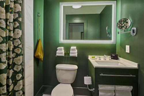 a green bathroom with a toilet and a sink at The Partridge Inn Augusta, Curio Collection by Hilton in Augusta