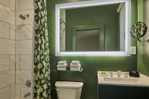 a green bathroom with a sink and a mirror at The Partridge Inn Augusta, Curio Collection by Hilton in Augusta