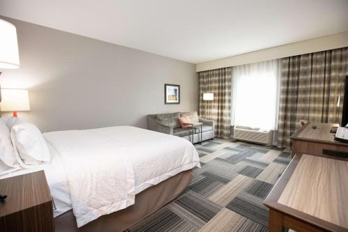 Hampton Inn & Suites - Toledo/Oregon في Oregon: غرفه فندقيه بسرير وكرسي