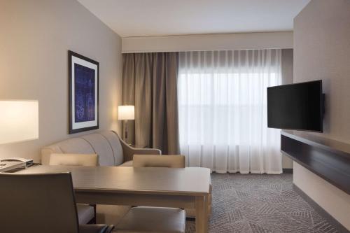 a living room with a couch and a television in a hotel room at Embassy Suites by Hilton Kansas City Olathe in Olathe