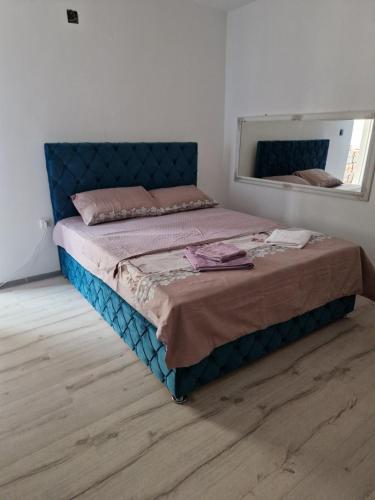 a bedroom with a bed with a blue headboard and a mirror at Apartmani relax in Leskovac